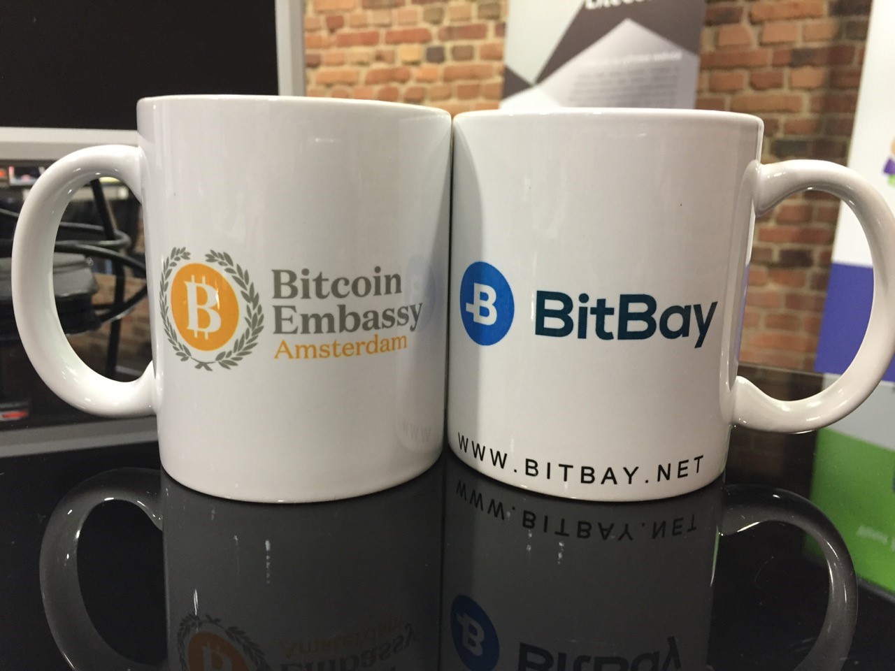 Bitcoin Embassy mug alongside with the mug of a sponsor